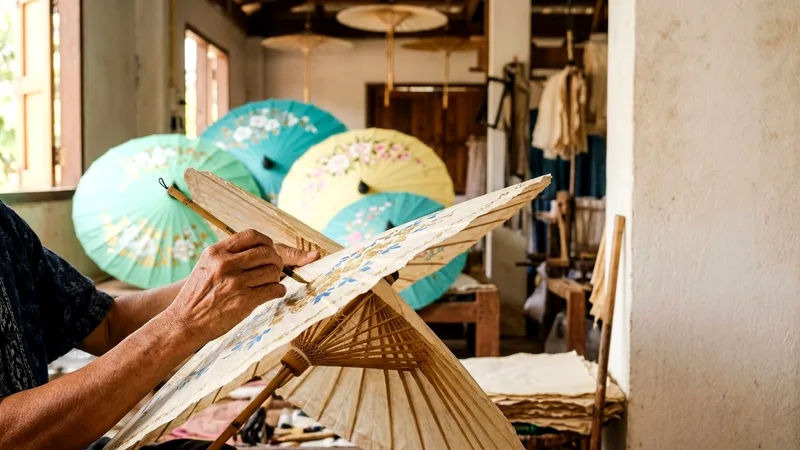 Hands painting floral designs on a Bo Sang paper umbrella
